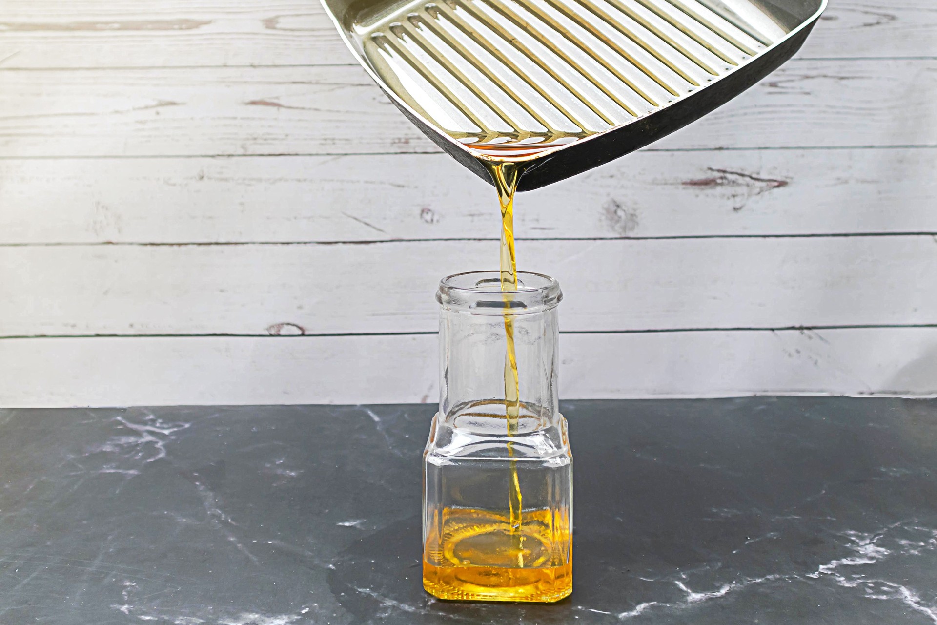 Vierta el aceite de cocina usado de la sartén en la botella de vidrio. El aceite de cocina viejo o usado se puede reciclar en biodiesel.